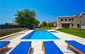 a swimming pool with two blue benches and a house at Villa Soricevi Dvori in Barat