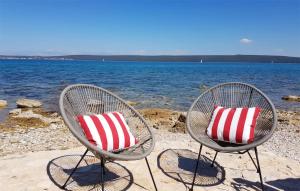 due sedie con cuscini rossi e bianchi su una spiaggia di Amazing Apartment In Dobropoljana a Dobropoljana