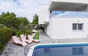 a white house with a swimming pool and pink chairs at Cld688, Villa Vlahov I in Šibenik +36 photos