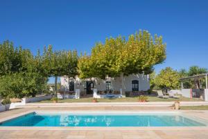 a swimming pool in front of a house with trees at Finca Olivo Llorón in Montilla