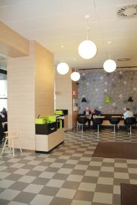 a lobby with people sitting at tables in a cafeteria at Hesehotelli Turku Linja-autoasema in Turku
