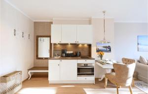 une cuisine avec des armoires blanches et une table et des chaises dans l'établissement Baltischer Hof Apartment 25, à Boltenhagen