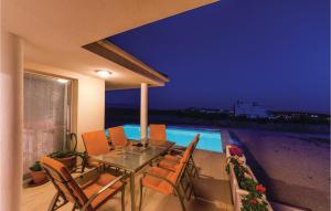 a glass table and chairs on a patio with a swimming pool at 3 Bedroom Lovely Home In Novalja in Novalja