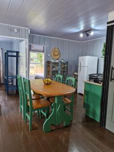 a kitchen with a wooden table and green chairs at Casinha Trilha da Guarda in Guarda do Embaú