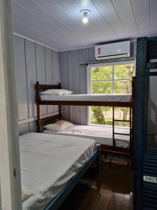two bunk beds in a room with a window at Casinha Trilha da Guarda in Guarda do Embaú