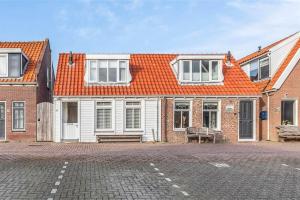 a house with an orange roof and a brick street at Viking in Egmond aan Zee