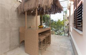 a bar with stools under a straw umbrella on a balcony at Lovely Apartment In Jesenice With Wifi in Jesenice