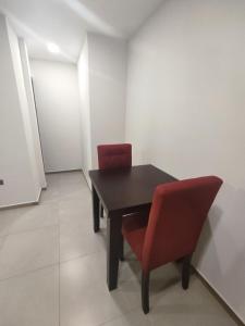 una mesa negra y 2 sillas rojas en una habitación en GZ GUEST HOUSE, en Cuenca