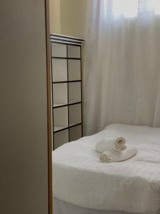 Ein weißes Handtuch liegt auf einem Bett neben einem Spiegel. in der Unterkunft Luna Loft in Mondesa