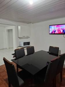 a dining room with a black table and chairs at Casa Acolhedora 04 no bairro Rio Branco in Caxias do Sul