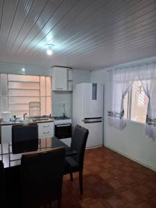 a kitchen with a table and chairs and a kitchen with a stove at Casa Acolhedora 04 no bairro Rio Branco in Caxias do Sul