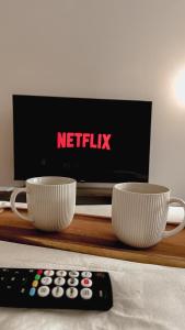 two coffee cups and a tv and a remote control at Prenoćište Katarina JUGOVO in Smederevo +14 photos