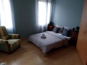 1 dormitorio con cama, silla y ventana en Le Coin Cozy, en Carhaix-Plouguer
