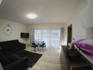 a living room with a couch and a table with a clock at Apartament Pięć Mórz z basenem in Sianozety