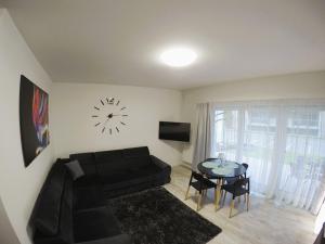 a living room with a couch and a table with a clock at Apartament Pięć Mórz z basenem in Sianozety