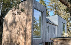 a house clad in wood with a large window at Awesome Home In Farsund With Wifi in Farsund