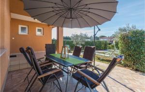 a table and chairs with an umbrella on a patio at 3 Bedroom Lovely Home In Savudrija in Savudrija