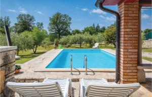 a swimming pool with white chairs in front of a house at 2 Bedroom Awesome Home In Rovinj in Spanidiga