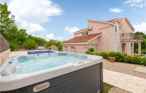 a large hot tub in a yard next to a house at Cozy Home In Glavina Donja With Kitchen in Donja Glavina