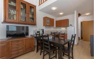a kitchen with a dining room table with chairs and a tv at Gorgeous Apartment In Njivice With Wifi in Njivice