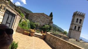 a man standing on a wall next to a building with a tower at LE DIMORE ARCANGELO Maria in Assisi