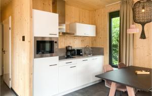 a kitchen with white cabinets and a table at Awesome Stacaravan In Callantsoog in Callantsoog