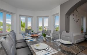 une salle à manger avec une table, des chaises et des fenêtres dans l'établissement Amazing Home In Donji Prolozac, à Donji Proložac
