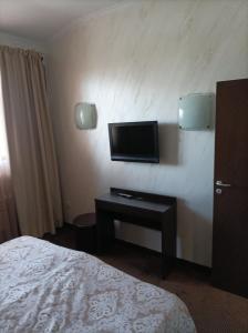a hotel room with a bed and a tv on a wall at Банско in Bansko