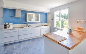 una cucina con armadi bianchi e parete blu di Lovely Home In Saint-Germain-Sur-Ay a Bretteville-sur-Ay