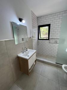 a white bathroom with a sink and a mirror at Altos de Las Sierras in Cosquín