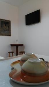 a plate on a table with a tv on the wall at Pousada Melodia do Mar in Cabo Frio