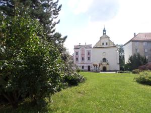 un grand bâtiment blanc avec une tour au-dessus d'une cour dans l'établissement Hotel Steiger, à Krnov
