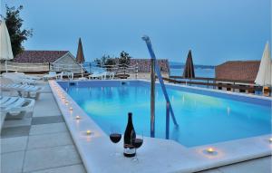 a bottle of wine sitting on a table next to a swimming pool at Apartment Pavlinka Bb Iv in Posedarje +24 photos