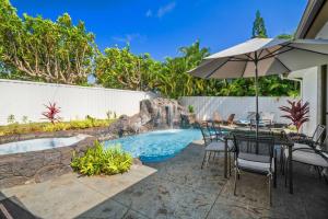 a patio with a table and an umbrella and a pool at Chic Princeville Villa Private Pool Relaxation and AC in Princeville