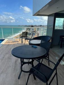 Una mesa y sillas en un balcón con vista al mar. en Luxury único excelente vista mar, en Maceió