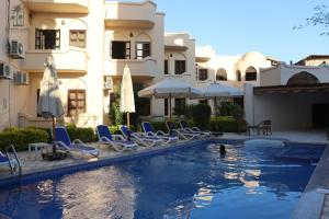 a pool with chairs and umbrellas next to a building at El Nakhil Hotel in Luxor