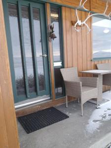 a porch with two chairs and a table and windows at Guesthouse Klambrasel in Skogar