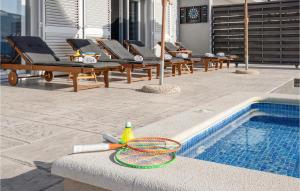 a pool with lounge chairs and a tennis racket next to it at Gorgeous Home In Srinjine in Srinjine +42 photos