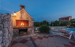 une cheminée dans un bâtiment en pierre à côté d'une piscine dans l'établissement Two-Bedroom Holiday Home In Zemunic Gornji, à Vlašnović