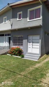 a house with white doors and flowers in the yard at Departamento Rosales Nro 2 in Valeria del Mar