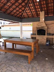 a table and benches under a pavilion with a brick oven at Belíssima cobertura duplex com vista para o mar in Arraial do Cabo