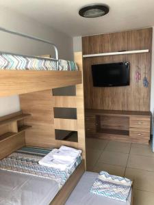 a room with a bunk bed with a flat screen tv at Belíssima cobertura duplex com vista para o mar in Arraial do Cabo +78 photos
