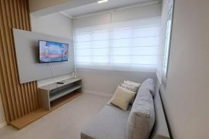 a living room with a couch and a tv at Apartamento aconchegante próximo Maria Fumaça in Bento Gonçalves