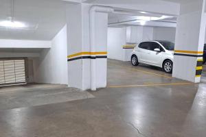 a parking garage with a white car parked in it at Apartamento aconchegante próximo Maria Fumaça in Bento Gonçalves