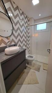 a bathroom with a sink and a toilet and a mirror at Apartamento aconchegante próximo Maria Fumaça in Bento Gonçalves +11 photos