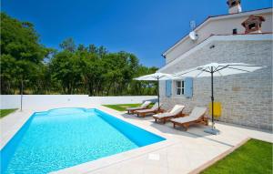 una piscina con sillas y una sombrilla junto a una casa en Villa Azura, en Pula