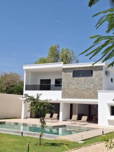 a white house with chairs and a swimming pool at villa eclore 2 in Sali Tapé