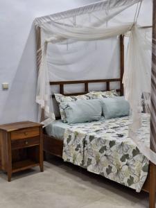 a bedroom with a canopy bed and a wooden table at villa eclore 2 in Sali Tapé +73 photos