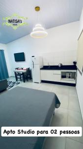 a room with a kitchen with a bed and a table at Studio aconchegante para duas pessoas in Bombinhas