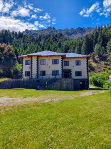 a large house in a field with a grass yard at Monoambiente en la Montaña - De Alojamientos Lago Puelo in Lago Puelo